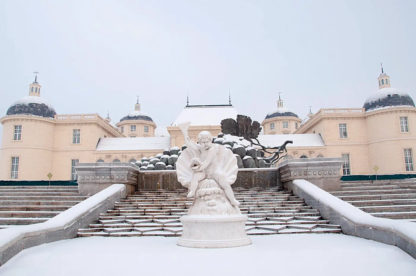 Snow on the stone steps and statue in front of the château